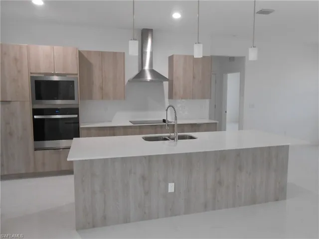 Kitchen featuring decorative light fixtures, modern cabinets, stainless steel appliances, and light stone counters