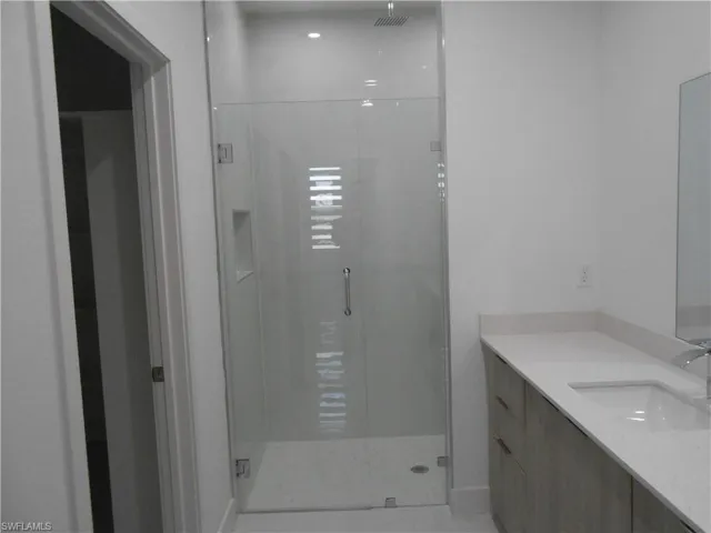 Full bathroom featuring a shower stall, vanity, and light tile patterned floors