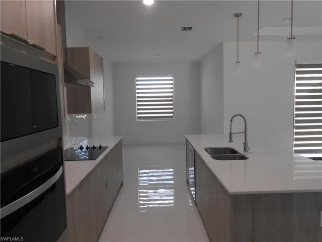 Kitchen featuring stainless steel oven, modern cabinets, built in microwave, and pendant lighting