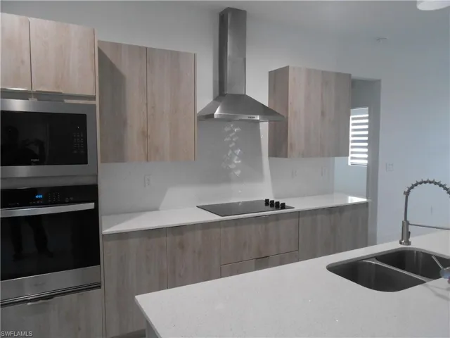 Kitchen with modern cabinets, stainless steel appliances, light stone counters, and light wood finish cabinetry