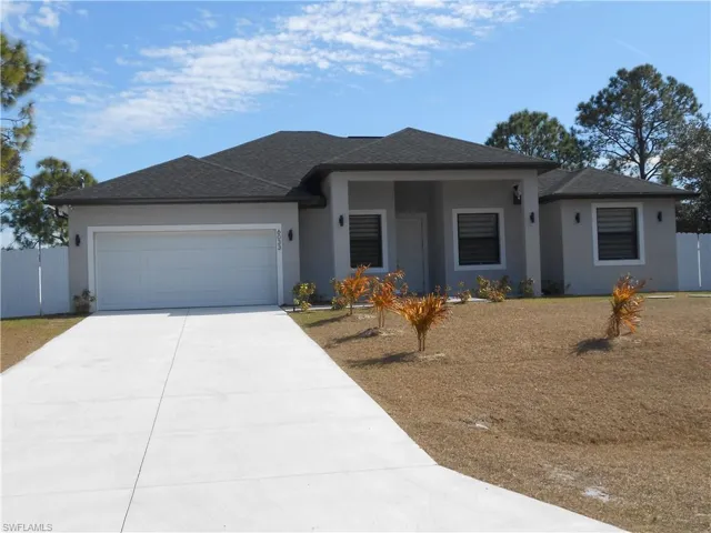 View of front of home with stucco siding, concrete driveway, roof with shingles, an attached garage, and a gate