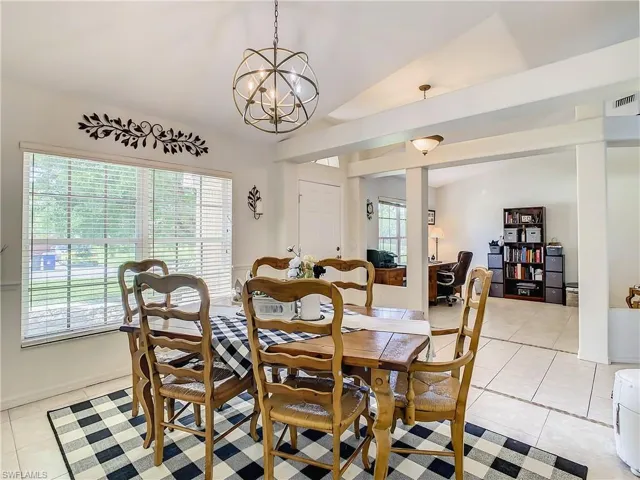 Tiled dining room with a chandelier, lofted ceiling, and plenty of natural light