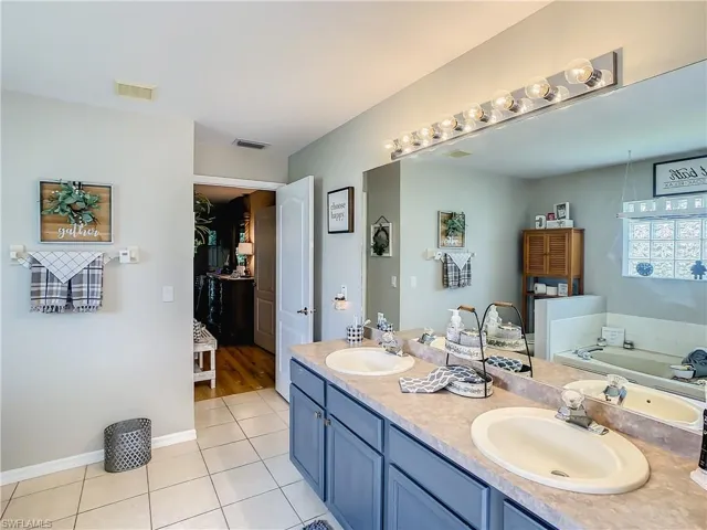 Bathroom featuring vanity, tile patterned flooring, and a bathing tub
