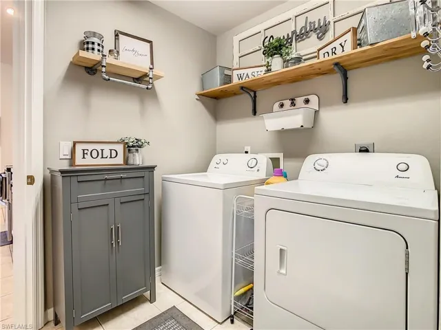 Laundry room with washer and clothes dryer, light tile patterned floors, and cabinets