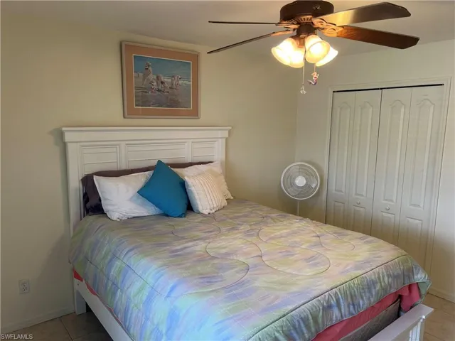 Bedroom with a closet, light tile patterned floors, and ceiling fan