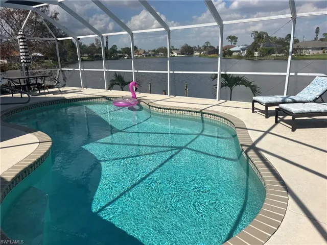 View of pool featuring a patio, a water view, and glass enclosure