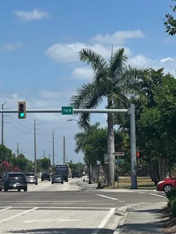 View of road featuring traffic lights, sidewalks, traffic signs, and curbs
