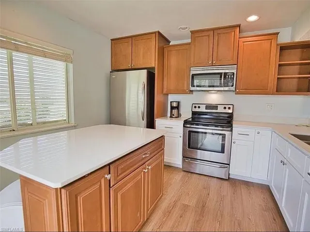 Kitchen featuring open shelves, stainless steel appliances, a center island, light wood finished floors, and dual tone cabinetry
