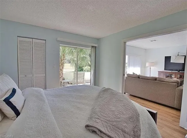 Bedroom featuring access to outside, a textured ceiling, wood finished floors, and a closet