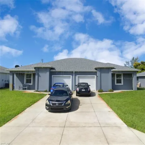 View of front of house featuring a front lawn, driveway, an attached garage, a shingled roof, and stucco siding
