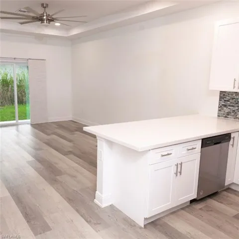 Kitchen with dishwasher, open floor plan, ceiling fan, white cabinets, and light wood-style floors