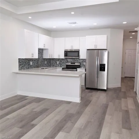 Kitchen with stainless steel appliances, white cabinetry, backsplash, and recessed lighting