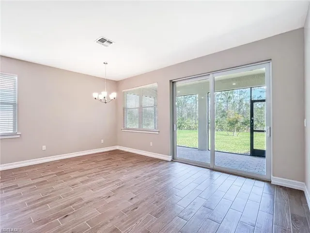 Unfurnished room with wood finish floors, plenty of natural light, and suspended lighting