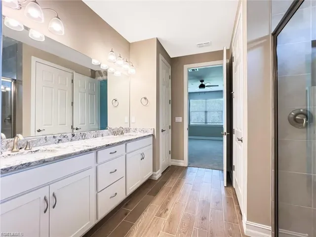 Full bath with a shower stall, double vanity, wood tiled floors, and ceiling fan