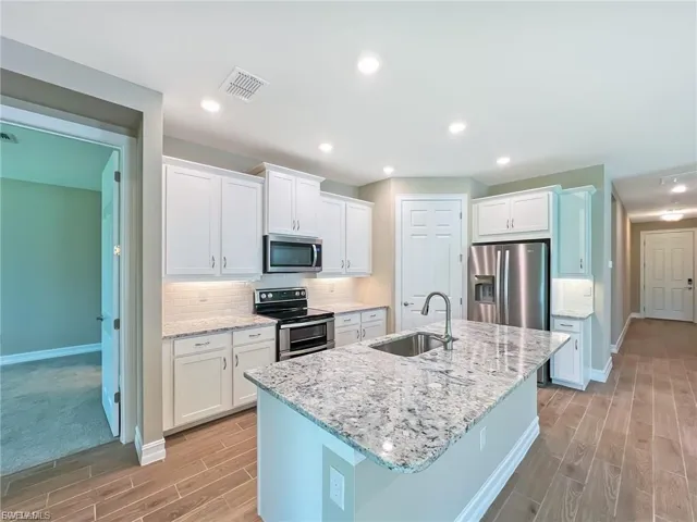 Kitchen featuring stainless steel appliances, decorative backsplash, wood tiled floors, and recessed lighting
