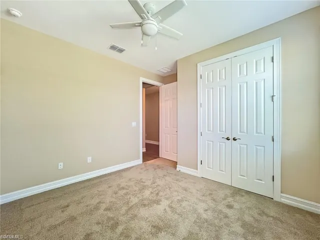 Unfurnished bedroom featuring carpet flooring, ceiling fan, and a closet