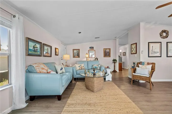 Living room featuring crown molding, lofted ceiling, light wood-type flooring, and ceiling fan