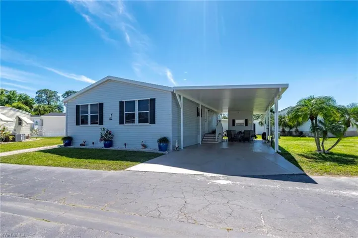 Manufactured / mobile home with a front yard, a carport, and driveway