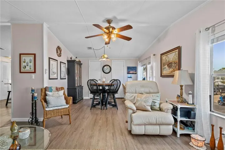 Living area featuring ornamental molding, wood finished floors, a ceiling fan, and lofted ceiling