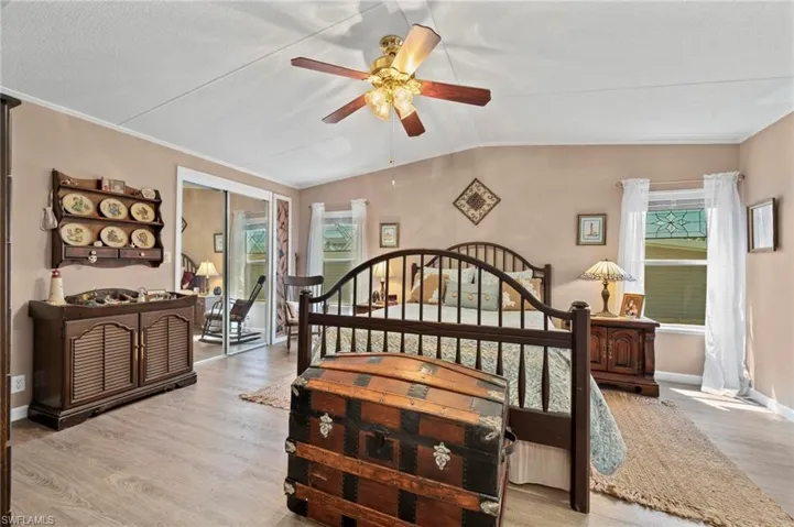 Bedroom with wood finished floors, lofted ceiling, a closet, a ceiling fan, and crown molding