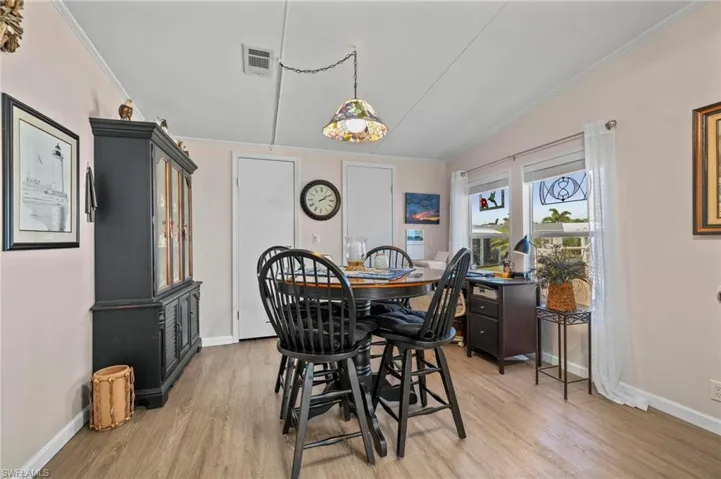 Dining area featuring crown molding, light wood-type flooring, and vaulted ceiling