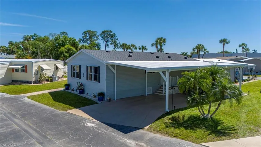 View of front of property with a front lawn, an attached carport, and driveway