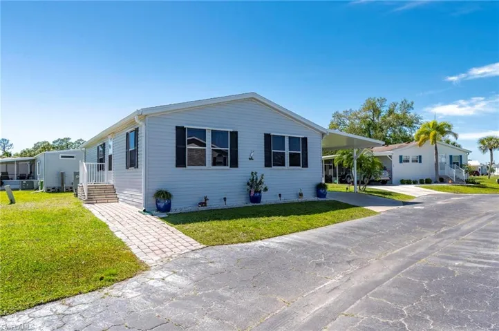 Manufactured / mobile home featuring a front yard, a carport, and concrete driveway