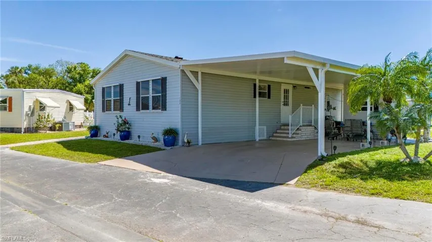 View of front of home with a front yard, a carport, concrete driveway, and entry steps