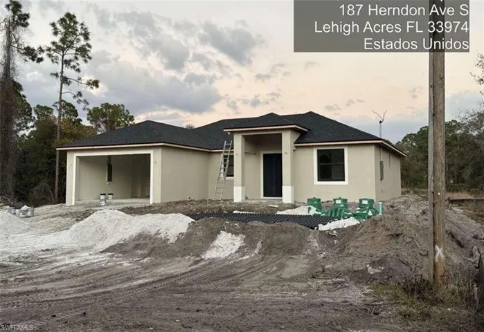 View of front facade with a patio, stucco siding, and an attached garage