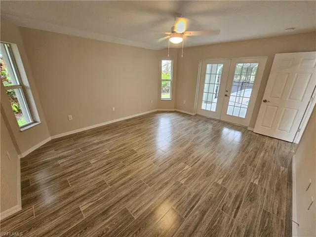 Empty room featuring ceiling fan, wood-type flooring, and french doors