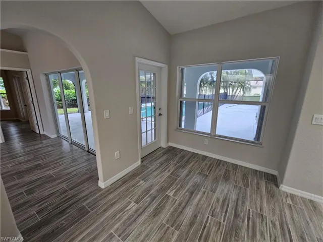 Foyer entrance featuring vaulted ceiling, dark hardwood / wood-style flooring, and a healthy amount of sunlight