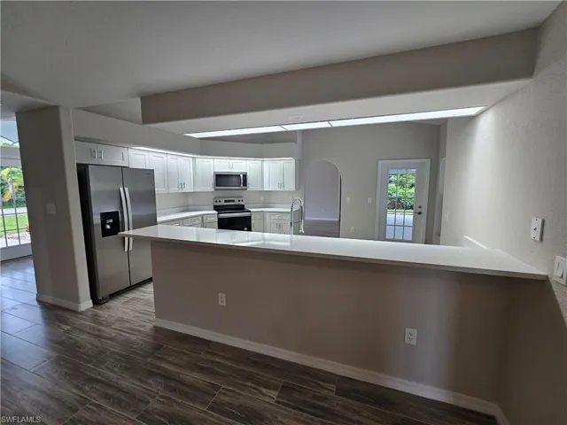 Kitchen featuring appliances with stainless steel finishes, kitchen peninsula, white cabinets, and sink