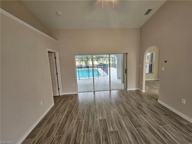 Spare room with high vaulted ceiling and wood-type flooring