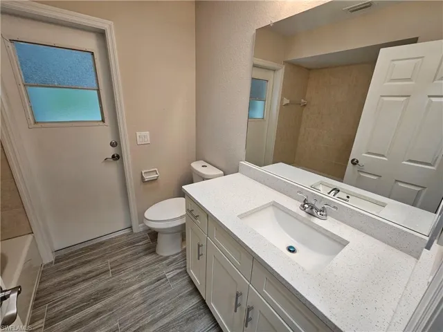 Full bathroom featuring toilet, tiled shower / bath combo, vanity, and tile patterned floors