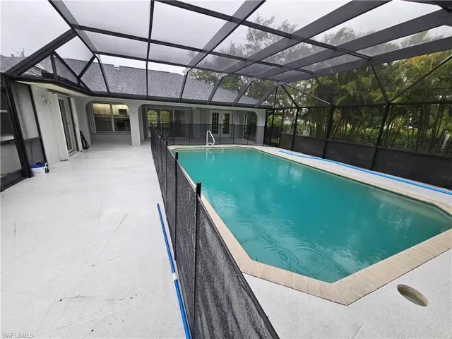 View of swimming pool with glass enclosure and a patio
