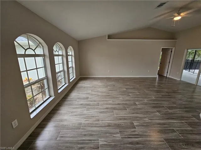 Unfurnished room featuring ceiling fan, plenty of natural light, and vaulted ceiling