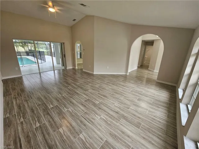 Unfurnished room featuring ceiling fan, hardwood / wood-style floors, and vaulted ceiling