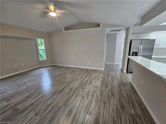 Unfurnished living room featuring ceiling fan, vaulted ceiling, and hardwood / wood-style flooring