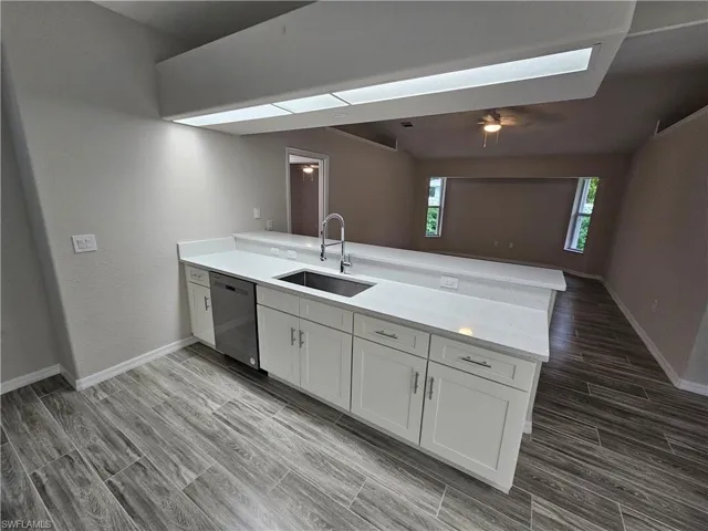 Kitchen featuring kitchen peninsula, sink, dishwasher, and a wealth of natural light