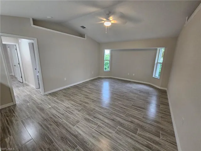 Empty room featuring ceiling fan, vaulted ceiling, and hardwood / wood-style flooring