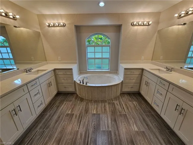 Bathroom with tiled bath, hardwood / wood-style flooring, and vanity