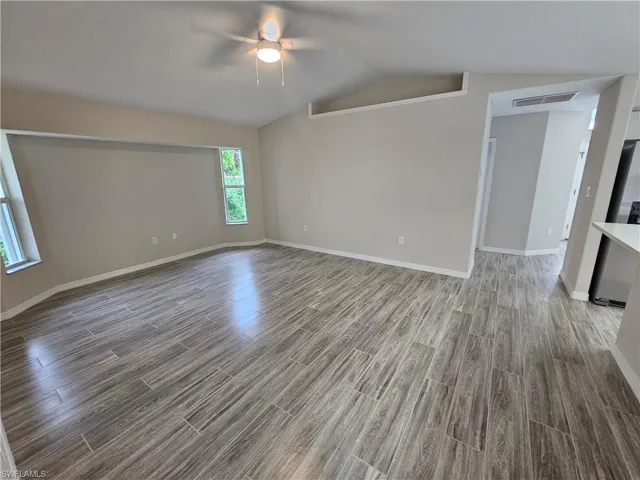 Unfurnished room with ceiling fan, lofted ceiling, and wood-type flooring