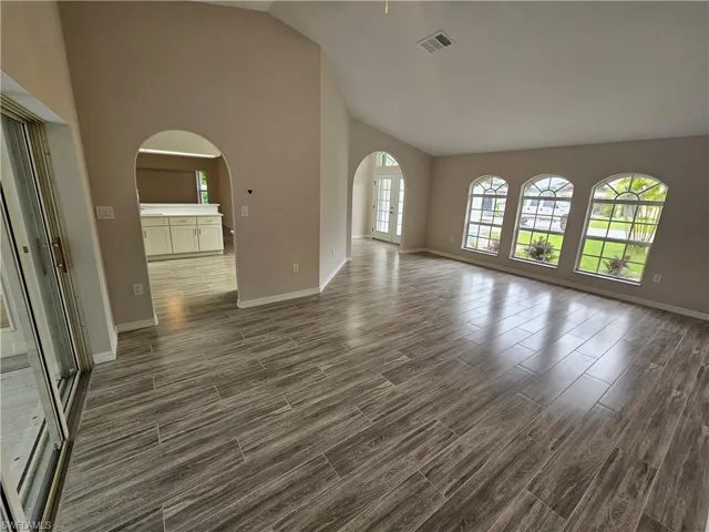 Unfurnished living room featuring high vaulted ceiling and hardwood / wood-style flooring