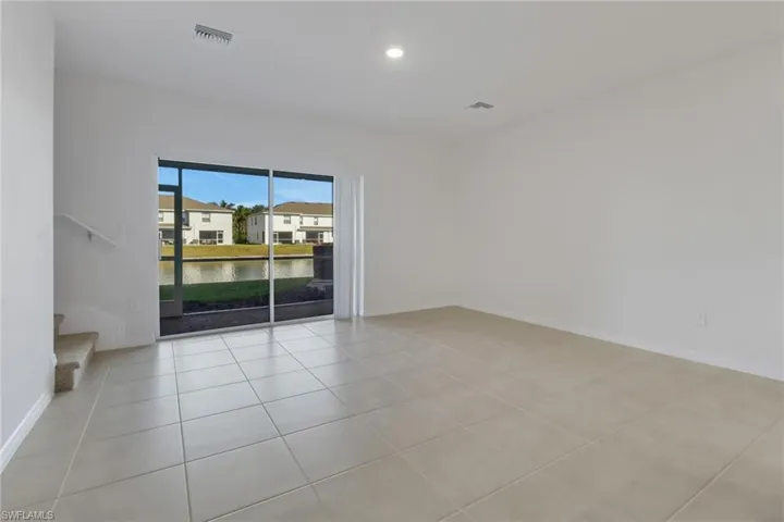 family room with light tile patterned floors and a water view