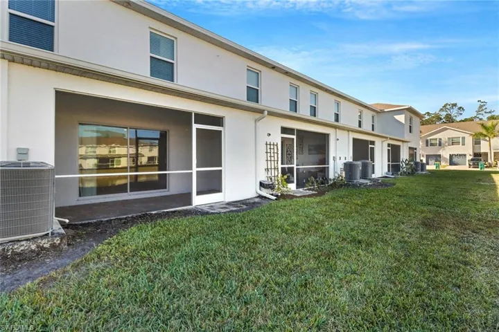 Rear view of property with a lawn and central air condition unit