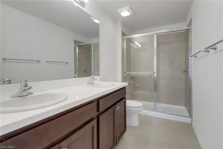 Primary Bathroom featuring tile patterned floors, vanity, toilet, and a shower with door