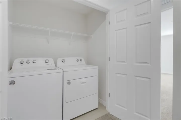 Laundry room with light colored carpet and washer and dryer