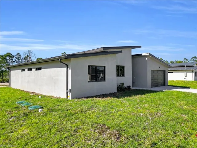 View of property exterior with a lawn, stucco siding, a garage, and driveway
