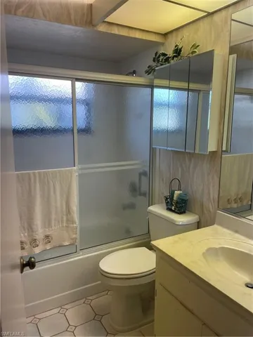 Full bathroom with shower / bath combination with glass door, vanity, and toilet