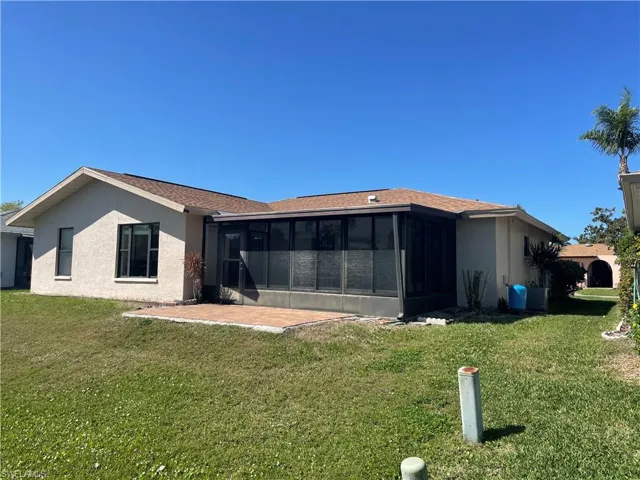 Rear view of property with a lawn, a sunroom, and stucco siding
